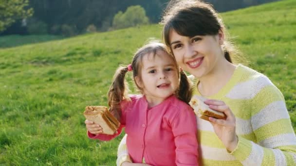 Madre e hija comiendo sándwiches en un picnic
 - Metraje, vídeo