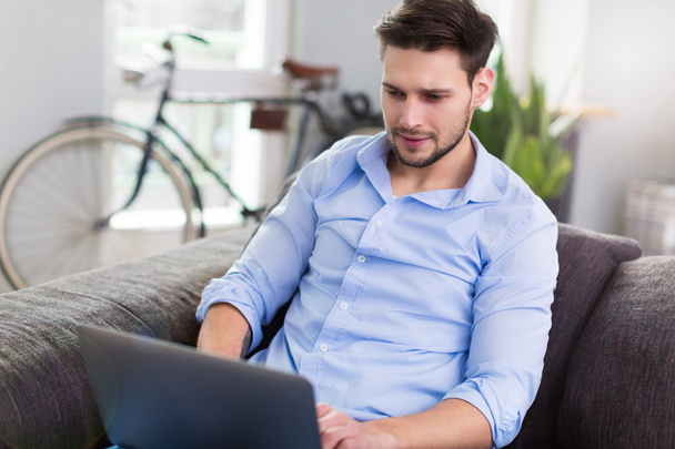 Man sitting on couch with laptop - Photo, Image
