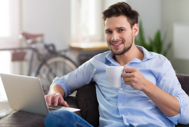 Man sitting on couch with laptop - Photo, image