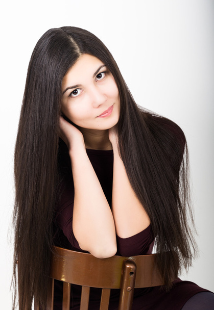 Beautiful asian young brunette in a dark dress sitting on a chair - Fotografie, Obrázek