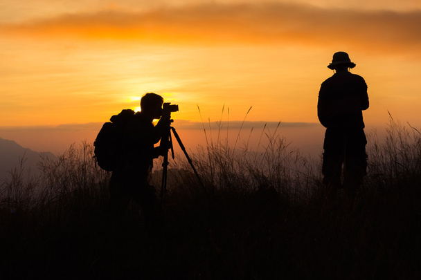 Silueta de un joven fotógrafo durante la puesta del sol
. - Foto, Imagen