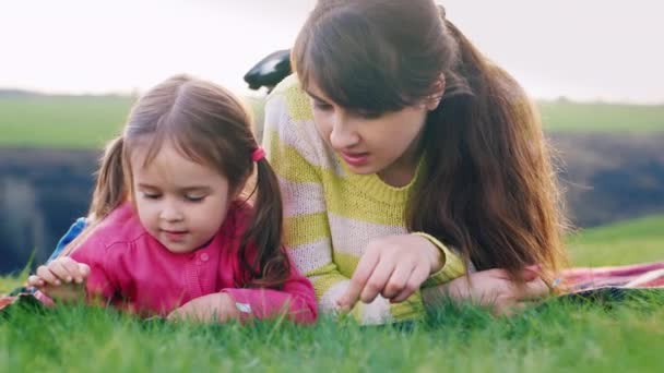 Mutter und Tochter liegen im Gras und reden - Filmmaterial, Video