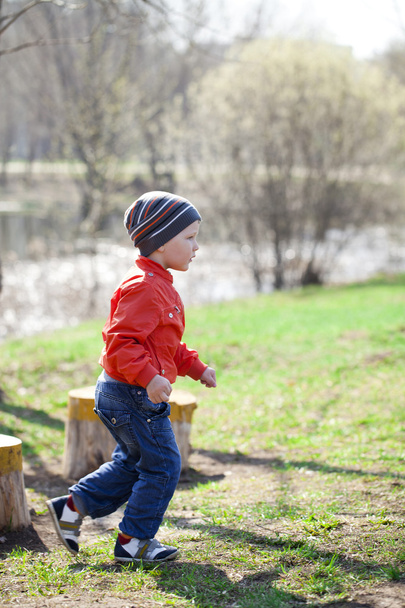 Baby boy in orange jaket and blue jeans - Фото, изображение