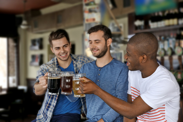 group of happy friends drinking beer in pub - 写真・画像