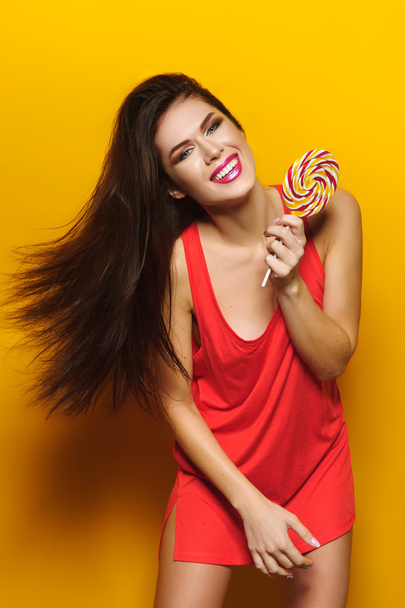 Красива молода дівчина з цукерками в руках посміхається і позує
  - Фото, зображення