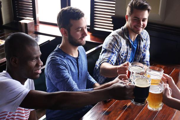 group of happy friends drinking beer in pub - Fotó, kép