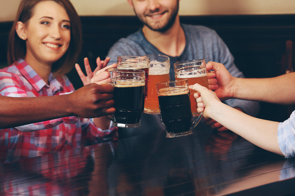 Group of happy friends drinking beer in pub - Foto, afbeelding