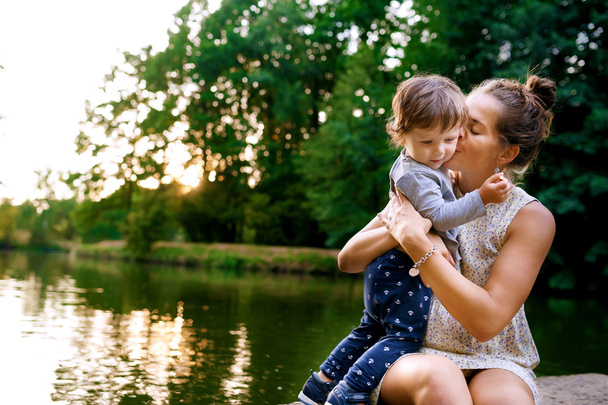 Joven madre embarazada caminando con su pequeño hijo en el parque de verano
 - Foto, Imagen