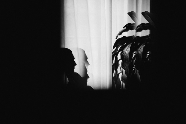 Mysterious man sitting with shadows by the window. Dark background - Photo, Image