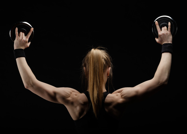 Молода струнка сильна м'язова жінка позує в студії з гантелі
  - Фото, зображення