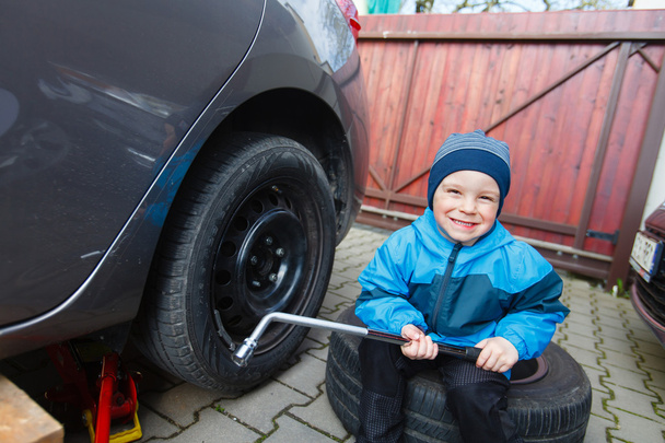 Junge montierte Reifen an Auto. - Foto, Bild