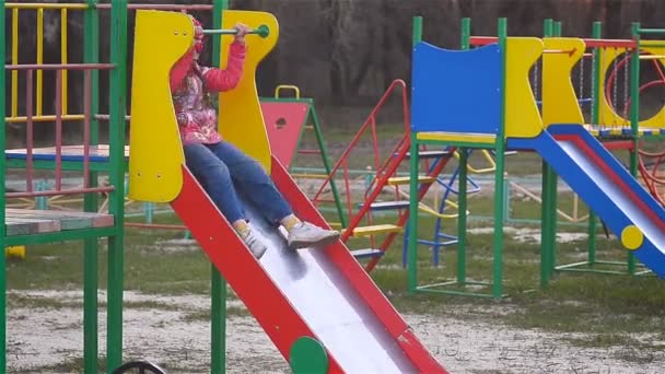Chica montando una montaña rusa en el patio de recreo
 - Imágenes, Vídeo