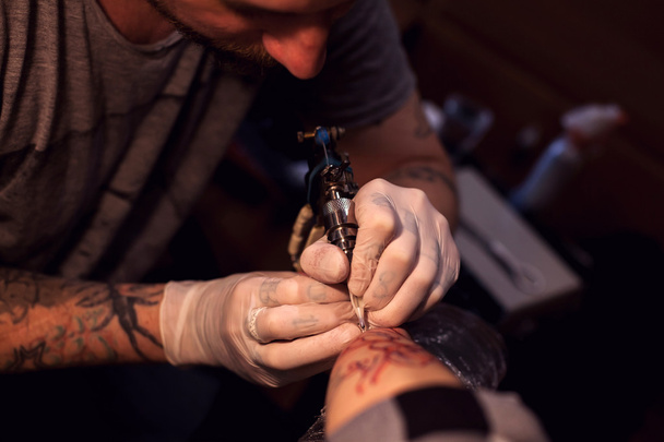 Tattoer usando máquina de tatuaje
 - Foto, imagen