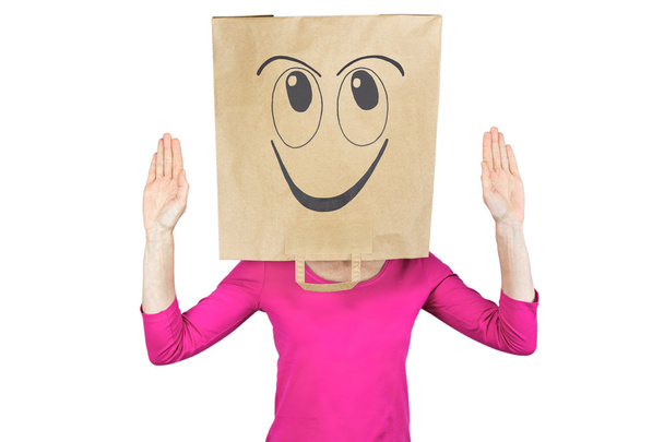 Γυναίκα που φοράει χαρτί τσάντα με ευτυχισμένη έκφραση του προσώπου στο κεφάλι - Φωτογραφία, εικόνα