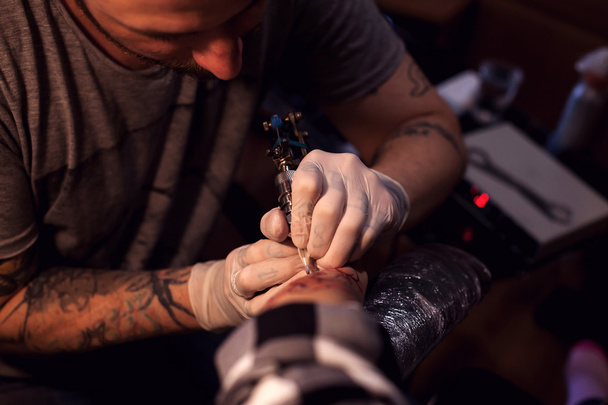 Tattoer usando máquina de tatuaje
 - Foto, Imagen