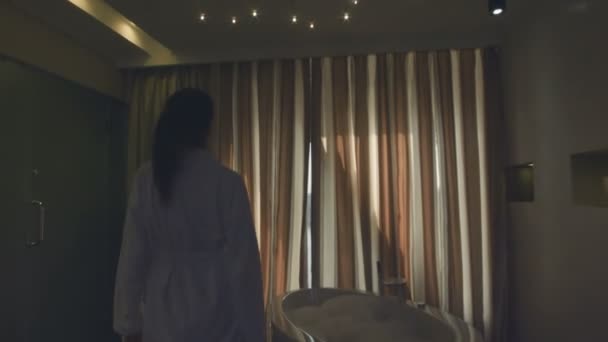 Het vrouwtje opent gordijnen op een venster - Video