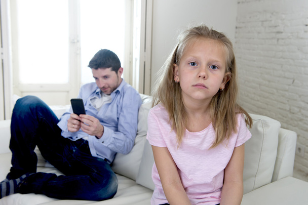 інтернет-залежний батько, використовуючи мобільний телефон, ігноруючи маленьку сумну дочку нудьгує самотньою і пригніченою
 - Фото, зображення