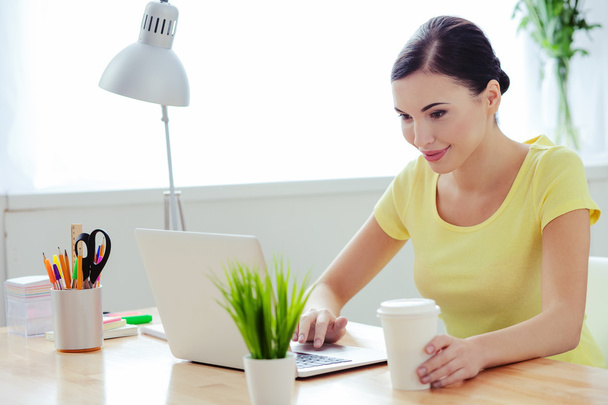 Cheerful young woman is working with laptop - Foto, immagini