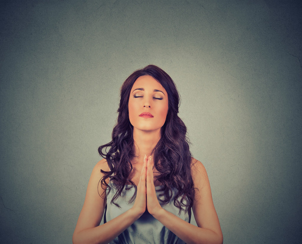 Young woman praying eyes closed isolated on gray wall background  - Valokuva, kuva