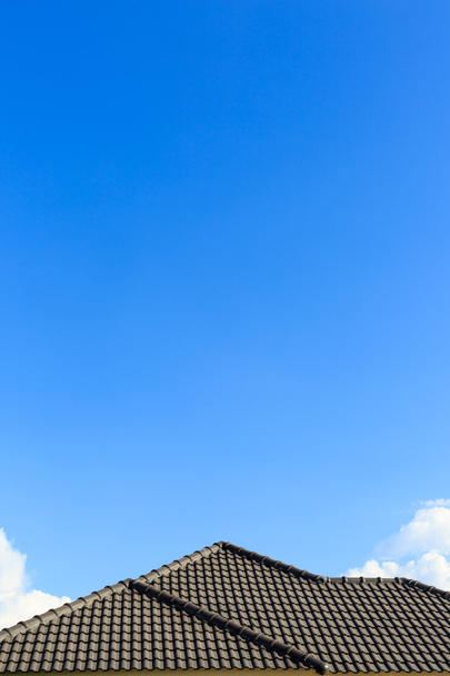 zwarte pannendak op een nieuw huis met helder blauwe hemelachtergrond - Foto, afbeelding