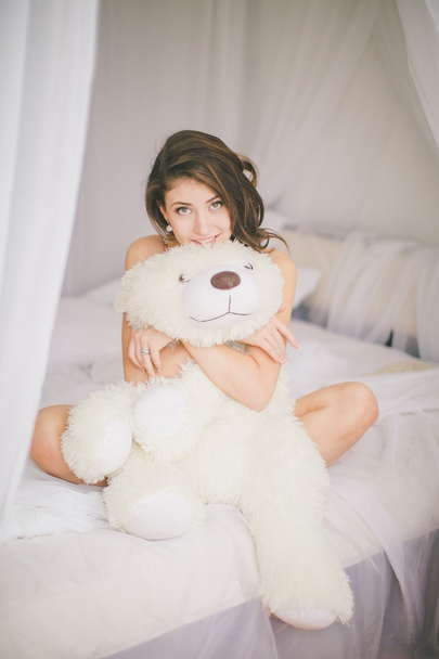 Brunette girl with toy bear in bedroom - Фото, зображення
