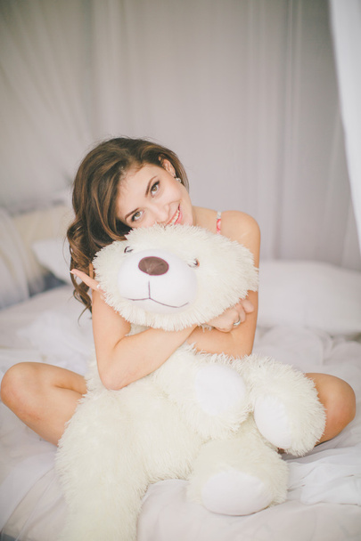 Brunette girl with toy bear in bedroom - Valokuva, kuva