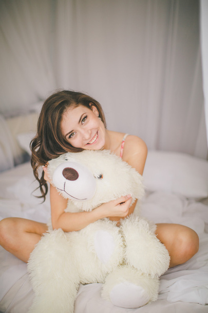 Brunette girl with toy bear in bedroom - Фото, зображення