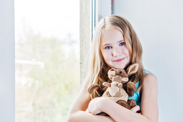 mooi meisje 8 jaar oud spelen met haar speelgoed grote en kleine kangoeroes  - Foto, afbeelding
