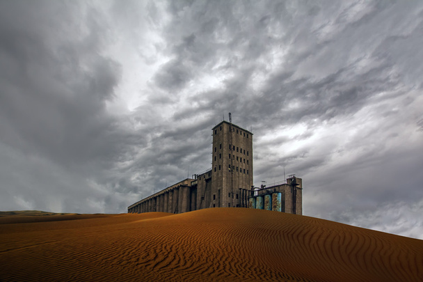 Postapokalyptischer Blick auf Getreideaufzug in der Wüste unter wolkenverhangenem Himmel - Foto, Bild