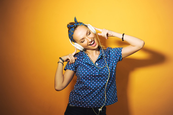 Young girl wearing headphones listening to music, singing and posing - Foto, imagen