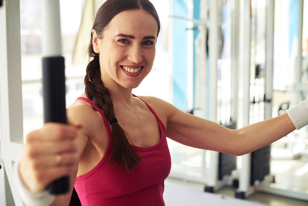 Caucasian smiling woman is working out at the gym - Photo, Image