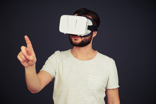 Ο άνθρωπος αγγίζει κάτι που φοράει ακουστικά υψηλής τεχνολογίας VR - Φωτογραφία, εικόνα