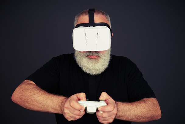 Vanhempi mies pelaa joystick yllään hi-tech VR kuulokkeet
 - Valokuva, kuva