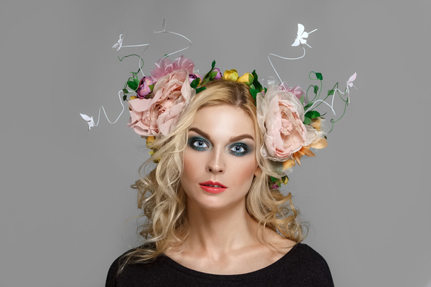 Portrait of a beautiful fashion model with red lips and blue eyes with coronet from flowers in curly blonde hair - Foto, immagini