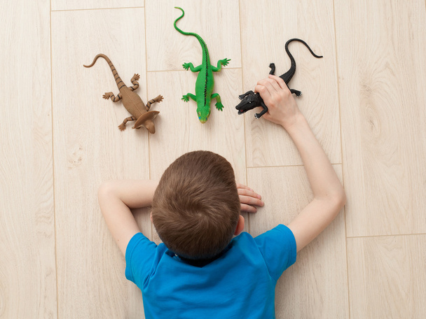 Junge spielt mit Spielzeug - Eidechse, Dinosaurier, Krokodil  - Foto, Bild