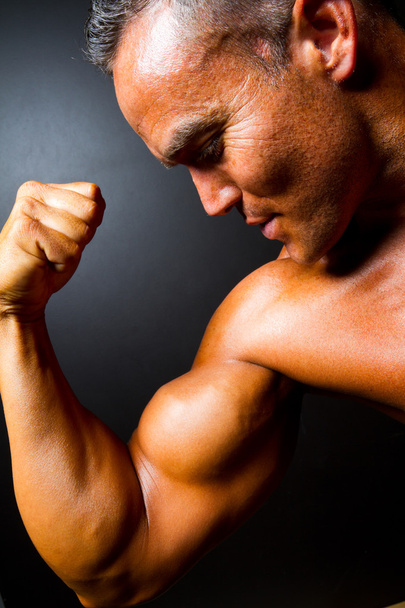 Muscular man showing strong arm - Foto, afbeelding