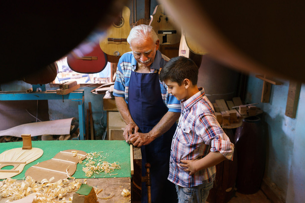 Viejo Lute Maker Enseñando Nieto Niño Chiseling Madera
 - Foto, imagen