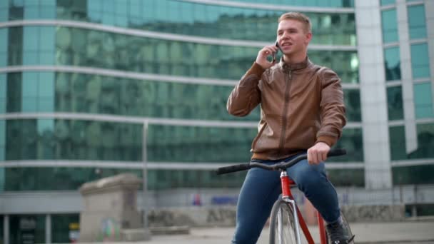 fiatal férfi kerékpárosok beszél a telefonon, a belvárosi lassú mozgás - Felvétel, videó