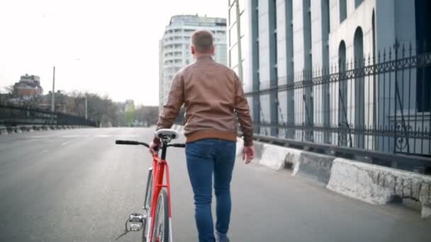 мужчина велосипедист идет рядом с велосипедом на улице замедленной съемки
 - Кадры, видео