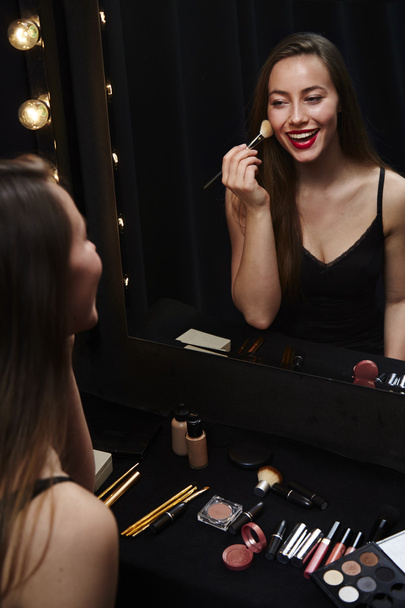 young woman applying make up - Foto, afbeelding