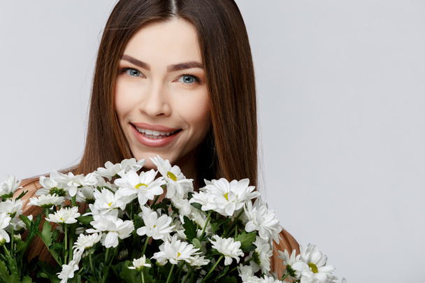 Beautiful Woman with Clean Fresh Skin holding flowers - Zdjęcie, obraz