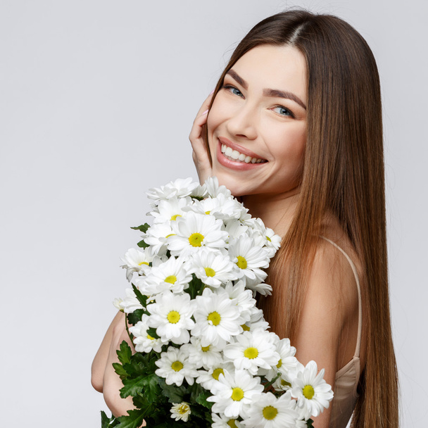 Beautiful Woman with Clean Fresh Skin holding flowers - Фото, зображення