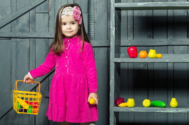 Little girl with plastic fruits and vegetables - Fotó, kép