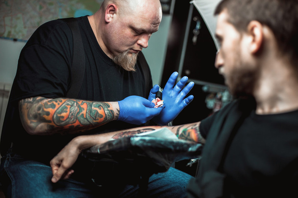 master tattooist makes a tattoo on the skin  - Foto, Imagen