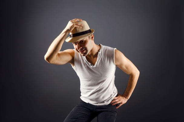 Man fashion model, stylish young man wearing fedora hat standing posing, over black background - 写真・画像