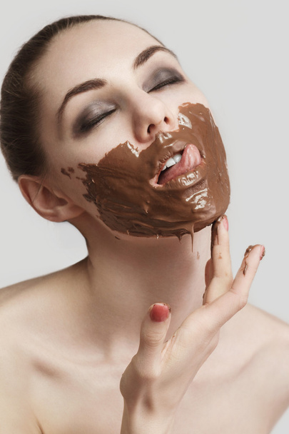 the girl licking the smeared chocolate from lips - Foto, Imagem
