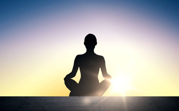 woman meditating in yoga lotus pose over sun light - Foto, afbeelding