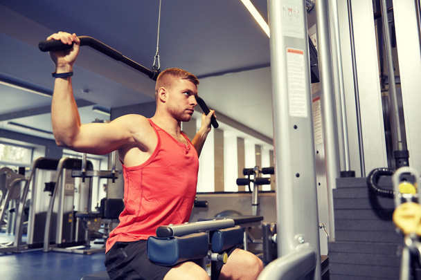 man flexing muscles on cable machine gym - Foto, afbeelding