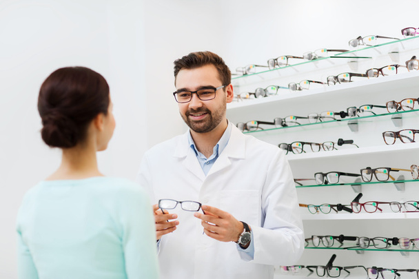 woman and optician showing glasses at optics store - Valokuva, kuva