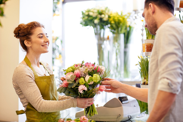 smiling florist woman and man at flower shop - Fotografie, Obrázek